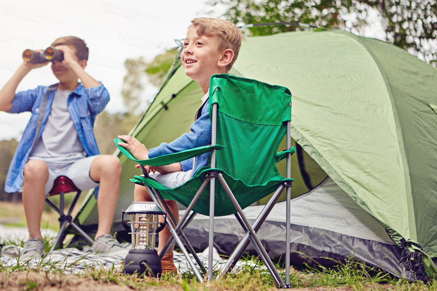 Buy stock photo Shot of two young brothers sitting at their campsite