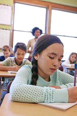 Buy stock photo Shot of a young girl sitting in class with her teacher and classmates blurred in the background