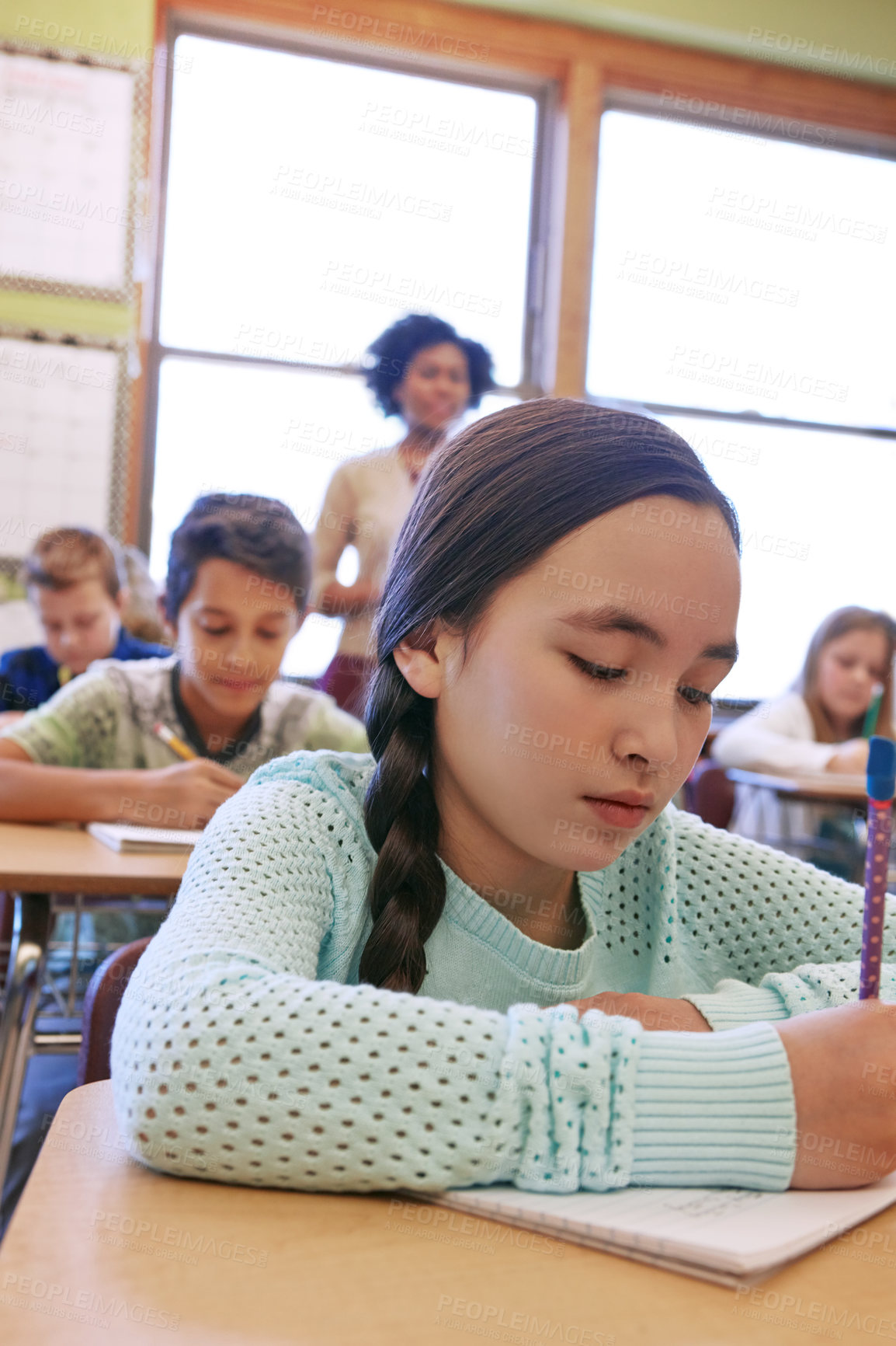 Buy stock photo Shot of a young girl sitting in class with her teacher and classmates blurred in the background