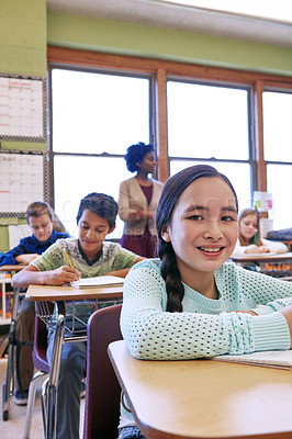 Buy stock photo Shot of a young girl sitting in class with her teacher and classmates blurred in the background