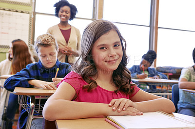 Buy stock photo Shot of a young girl sitting in class with her teacher and classmates blurred in the background