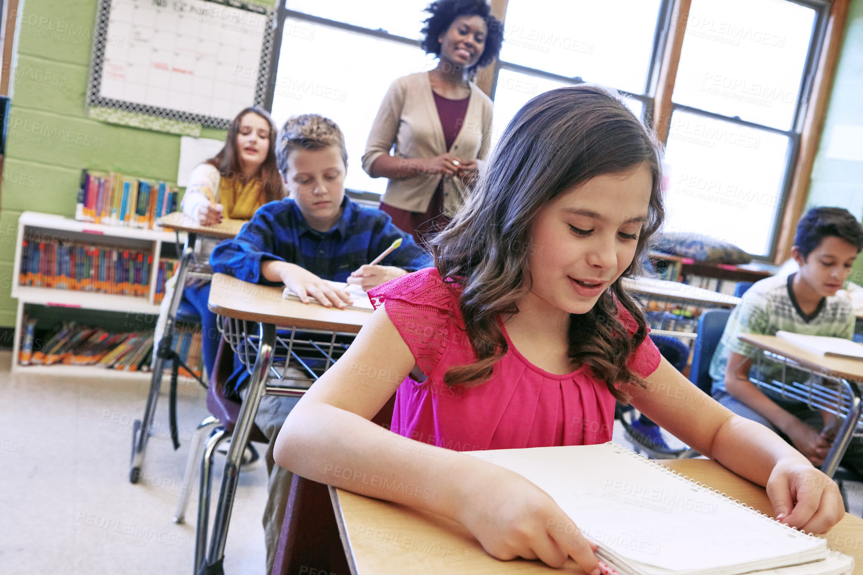 Buy stock photo Shot of a young girl sitting in class with her teacher and classmates blurred in the background