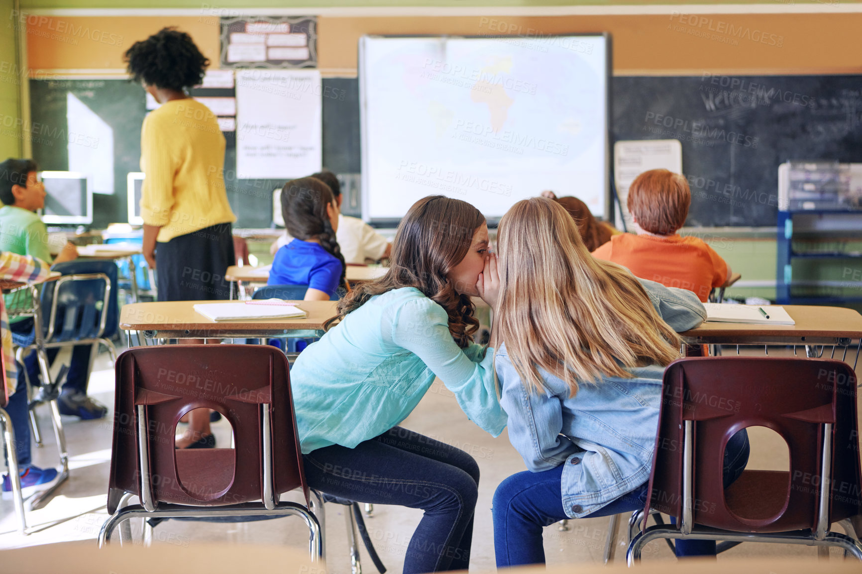 Buy stock photo Students, friends and whispering in classroom for secret, gossip or chatting during teaching lesson. Sneaky female learners sharing quiet information secretly in ear at class while teacher is busy