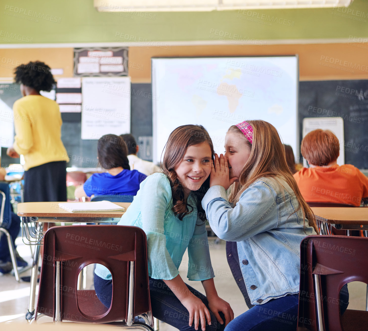 Buy stock photo Student, friends and whisper in classroom for secret, gossip or chatting during teaching lesson. Sneaky young female learners sharing quiet information secretly in ear at class while teacher is busy