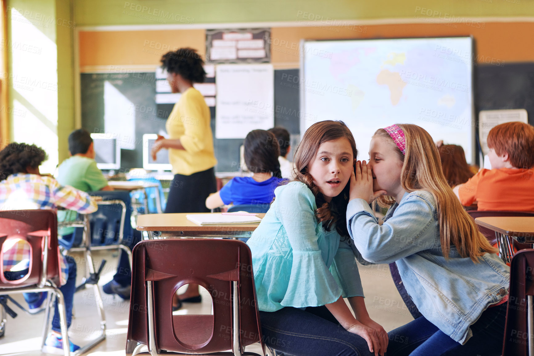 Buy stock photo School, friends and whispering in classroom for secret, gossip or chatting during teaching lesson. Sneaky female learners sharing quiet information secretly in ear at class while teacher is busy