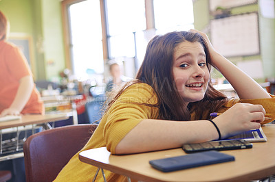 Buy stock photo Shot of a girl sitting in class with her classmates blurred in the background