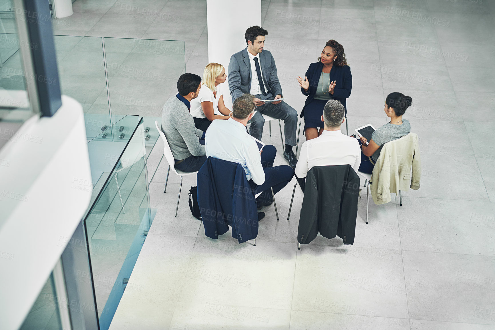 Buy stock photo High angle shot of a group of coworkers talking together while sitting in a circle in an office