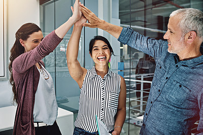 Buy stock photo Cropped shot of three colleagues high fiving in the office