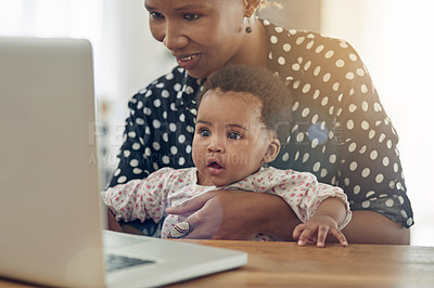 Buy stock photo Shot of a mother and her baby girl sitting in front of a laptop