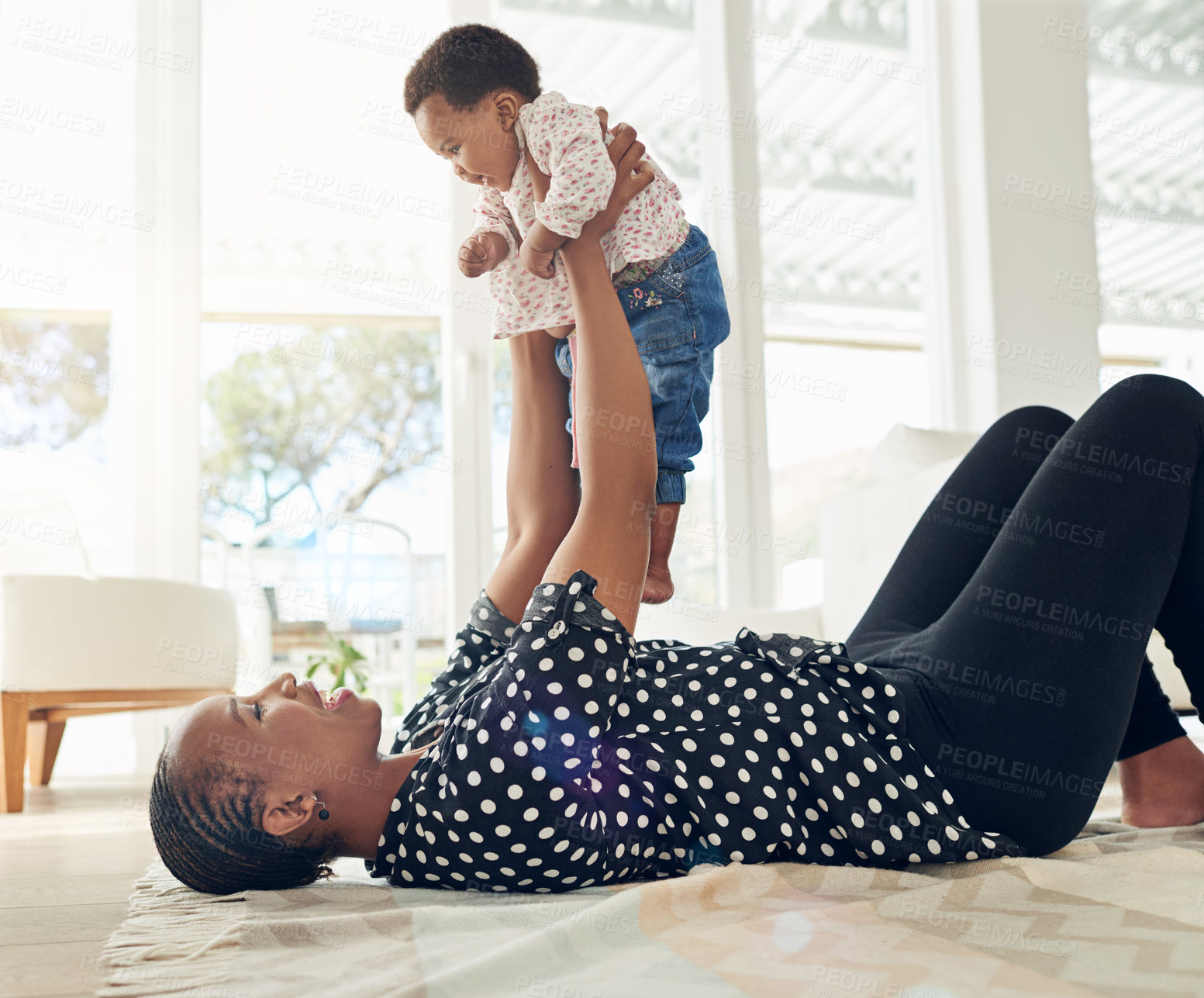 Buy stock photo Shot of a mother holding her baby girl up in the air