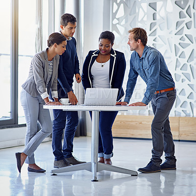 Buy stock photo Shot of a group of coworkers working together on a laptop in an office