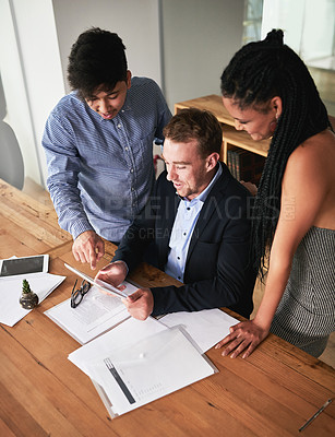 Buy stock photo Shot of a group of colleagues having a brainstorming session with a digital tablet in a modern office