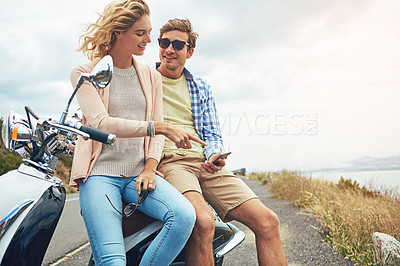Buy stock photo Shot of a couple using a cellphone while taking a break from their road trip