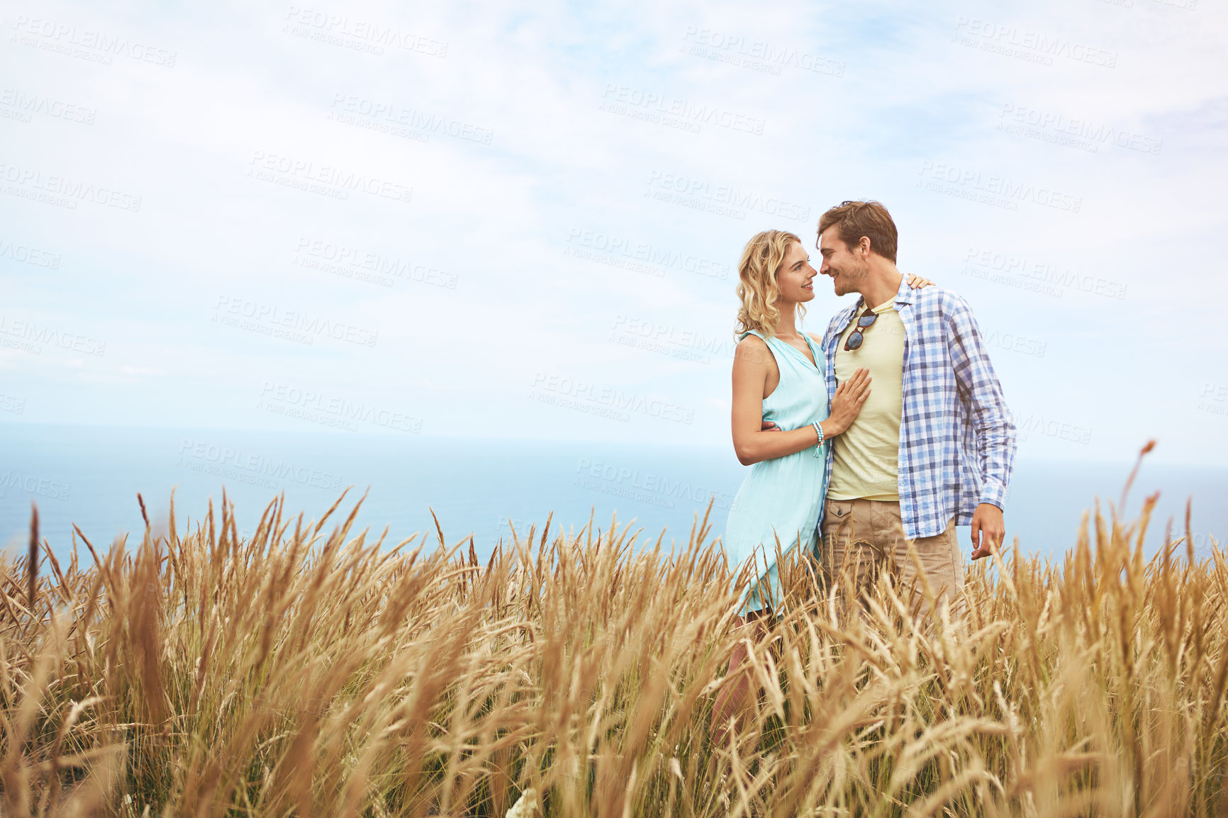 Buy stock photo Shot of a young couple in a field on a sunny day