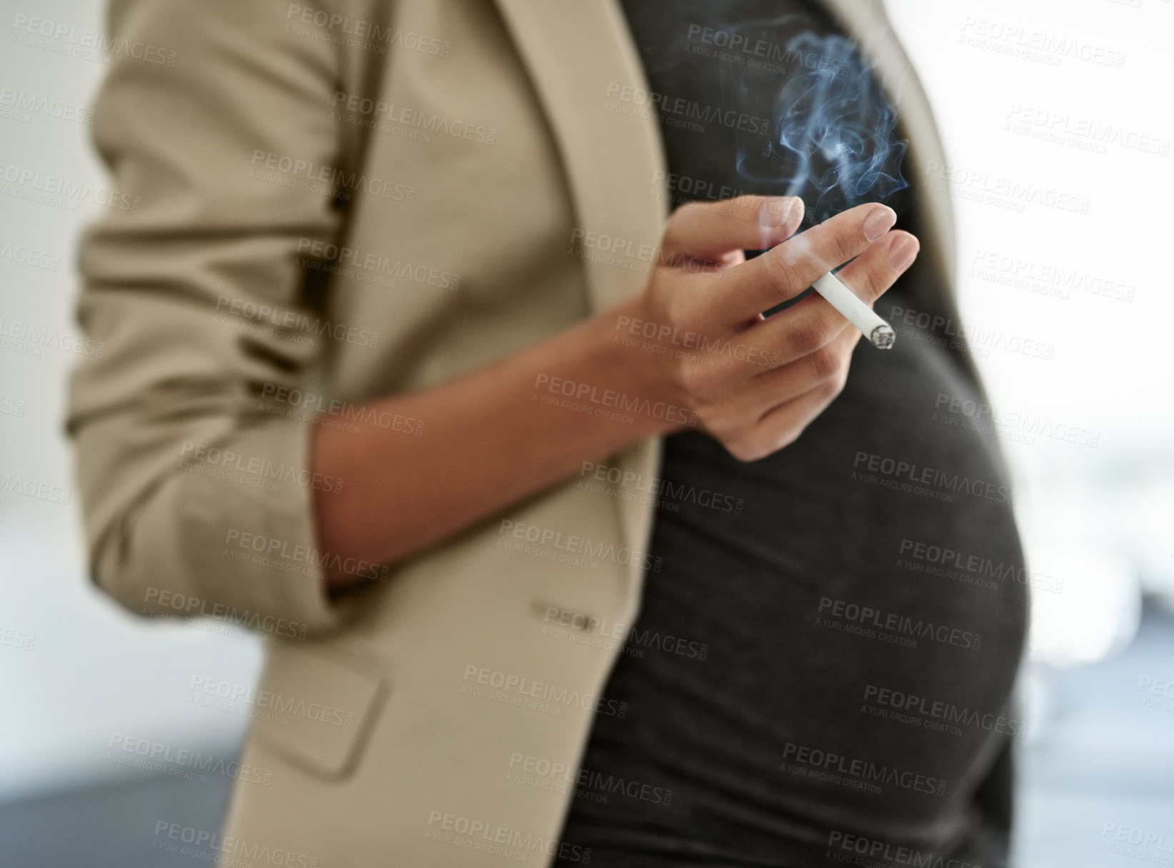 Buy stock photo Shot of a woman smoking a cigarette while preganant