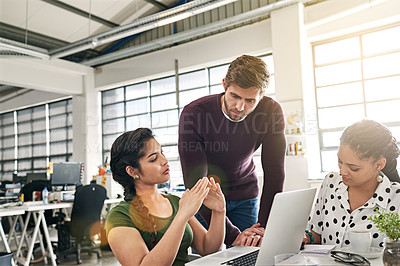 Buy stock photo Shot of a team of colleagues using a laptop together in a modern office