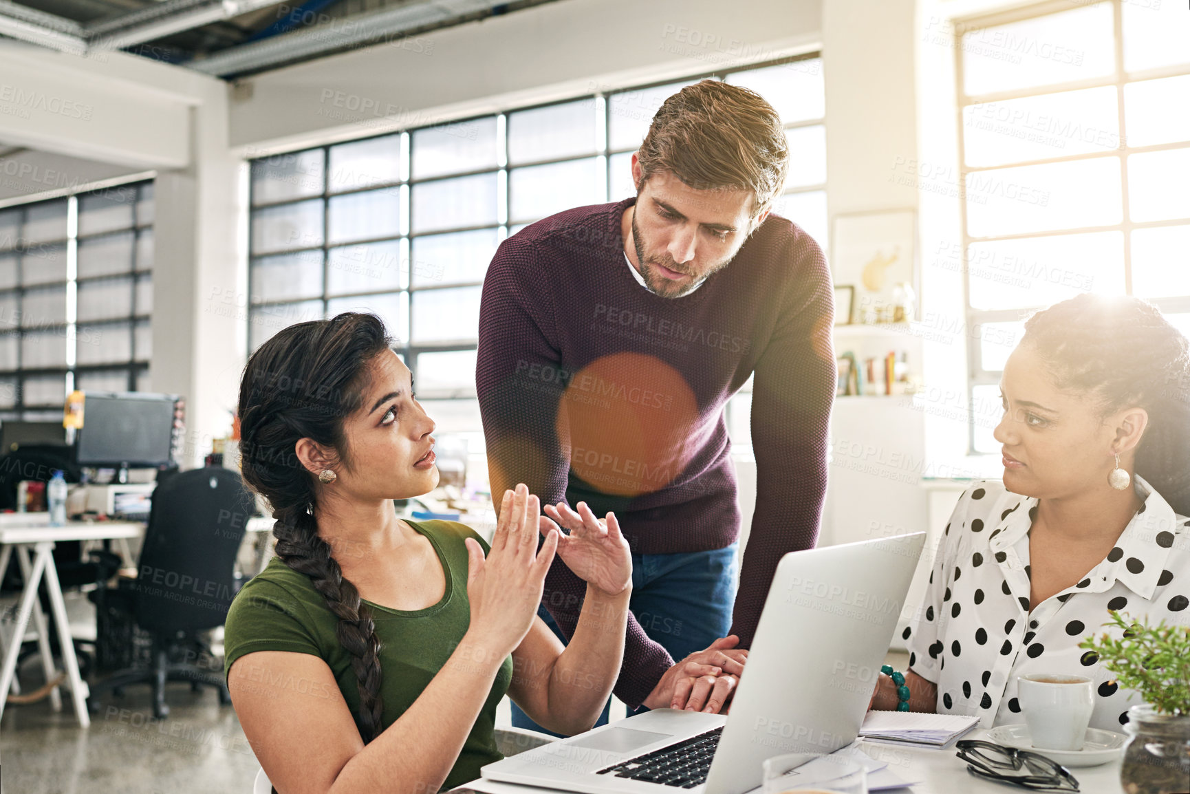 Buy stock photo Shot of a team of colleagues using a laptop together in a modern office