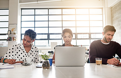 Buy stock photo Shot of a team of colleagues working at a desk in a modern office