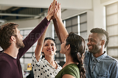 Buy stock photo Shot of a team of colleagues giving each other a high five in a modern office
