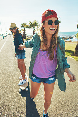 Buy stock photo Shot of two friends hanging out on the boardwalk with a skateboard