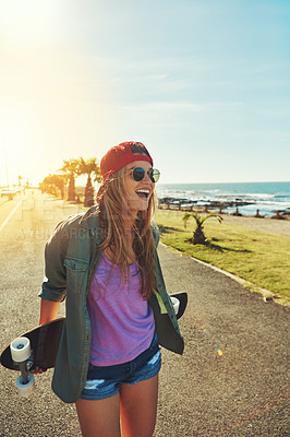 Buy stock photo Shot of a young woman hanging out on the boardwalk with her skateboard