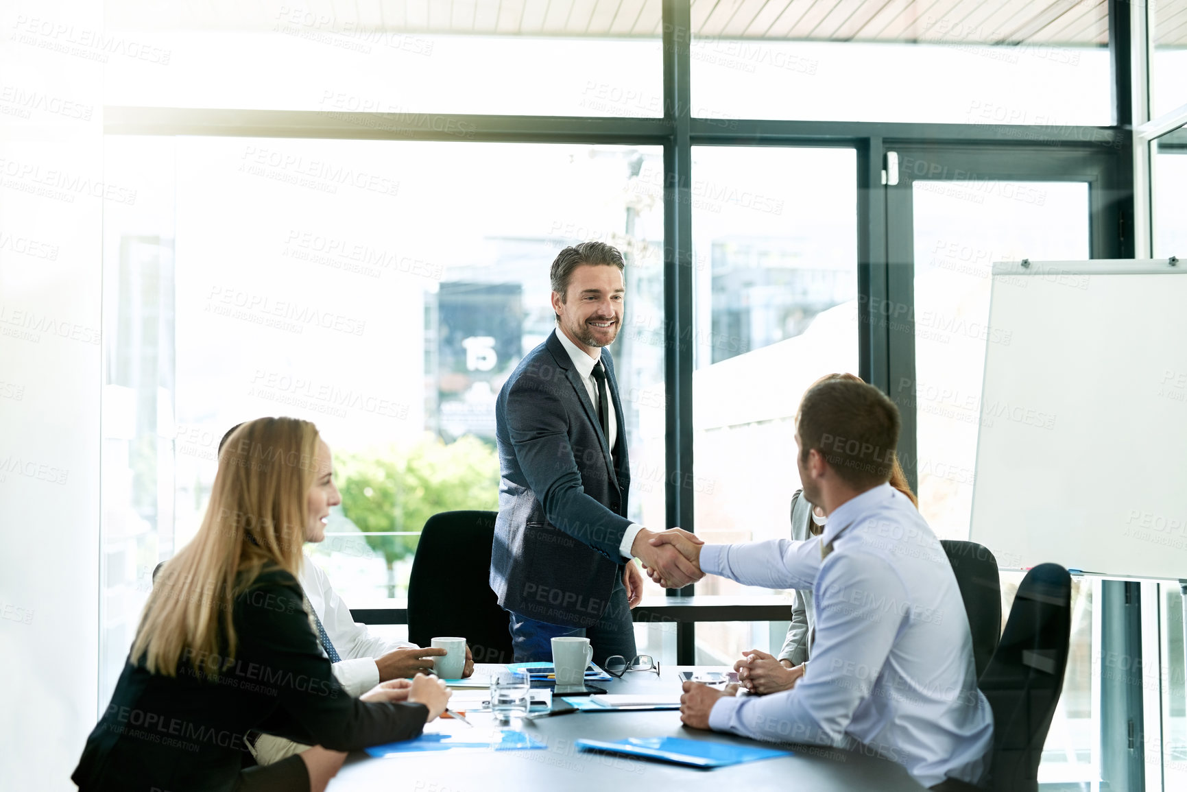 Buy stock photo Shot of colleagues shaking hands during a formal meeting in an office