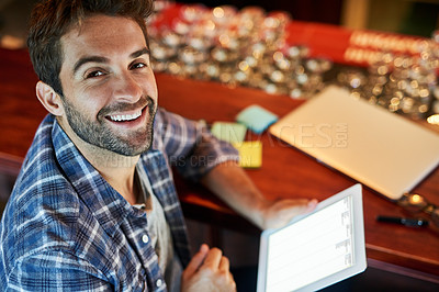 Buy stock photo Portrait of a handsome young man sitting in a cafe using a digital tablet