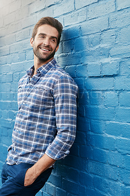 Buy stock photo Shot of a handsome young man leaning against a wall
