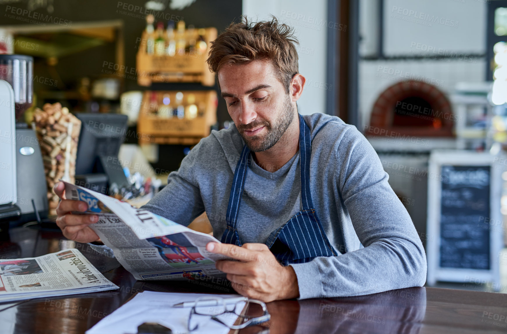 Buy stock photo Small business, cafe and man at table with newspaper, paperwork and relax in coffee shop. Reading, working and restaurant manager, waiter or owner checking news for service industry startup economy