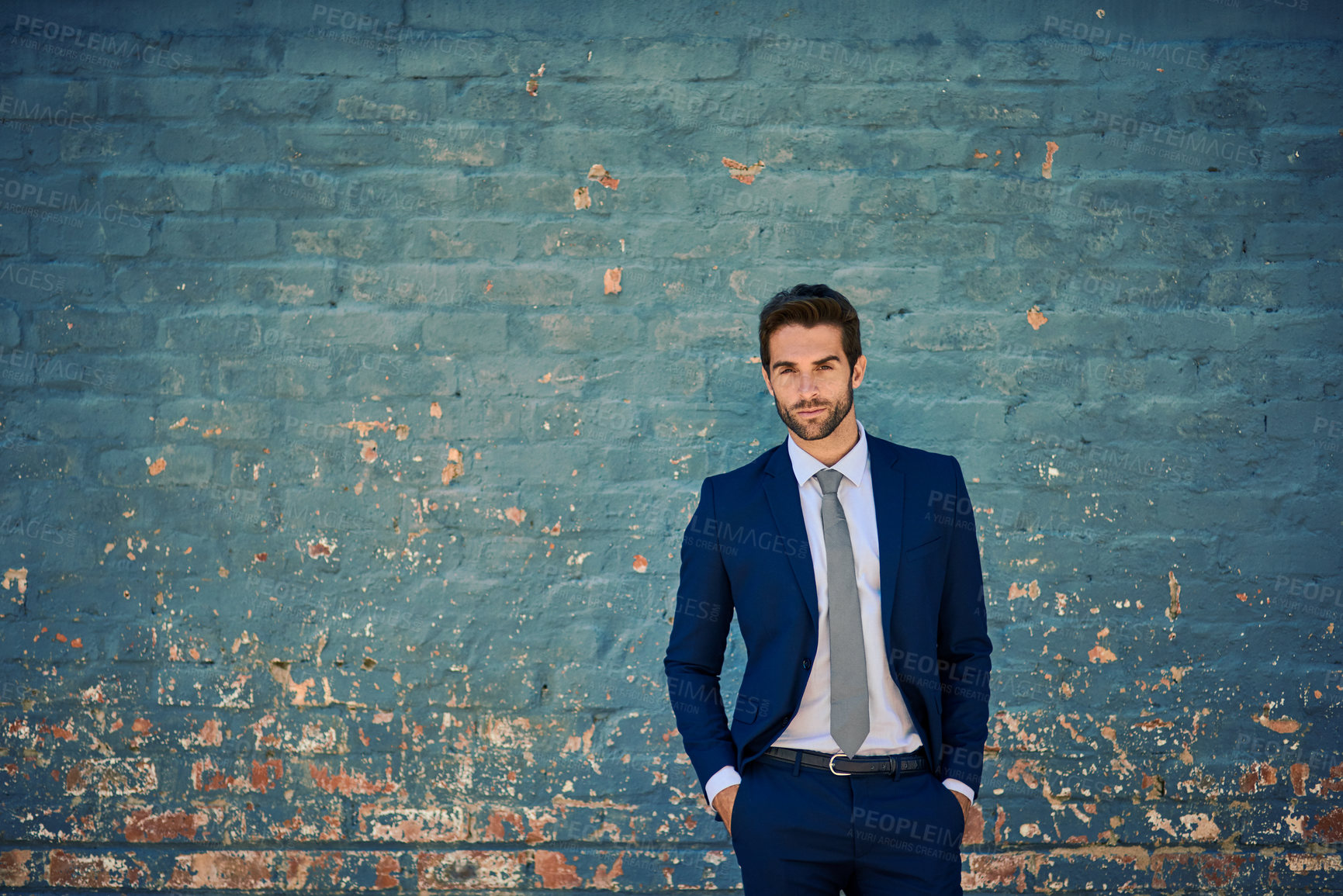 Buy stock photo Portrait of a young corporate businessman standing against a brick wall