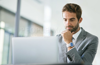 Buy stock photo Cropped shot of a handsome young businessman working on a laptop in an office