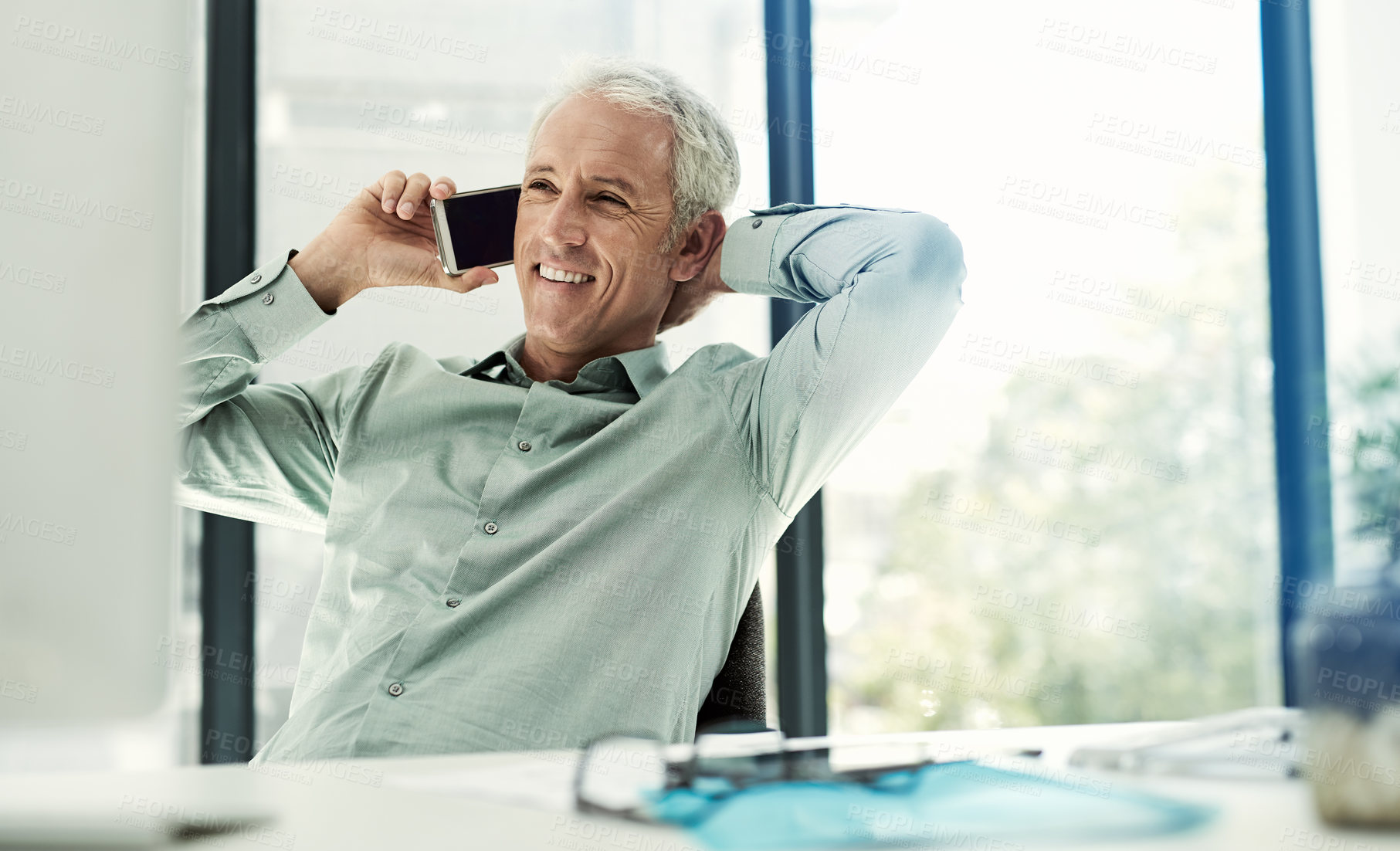 Buy stock photo Shot of a mature businessman talking on the phone while working at his desk in an office