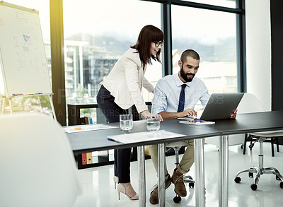 Buy stock photo Shot of two colleagues working together on a laptop at a desk in an office