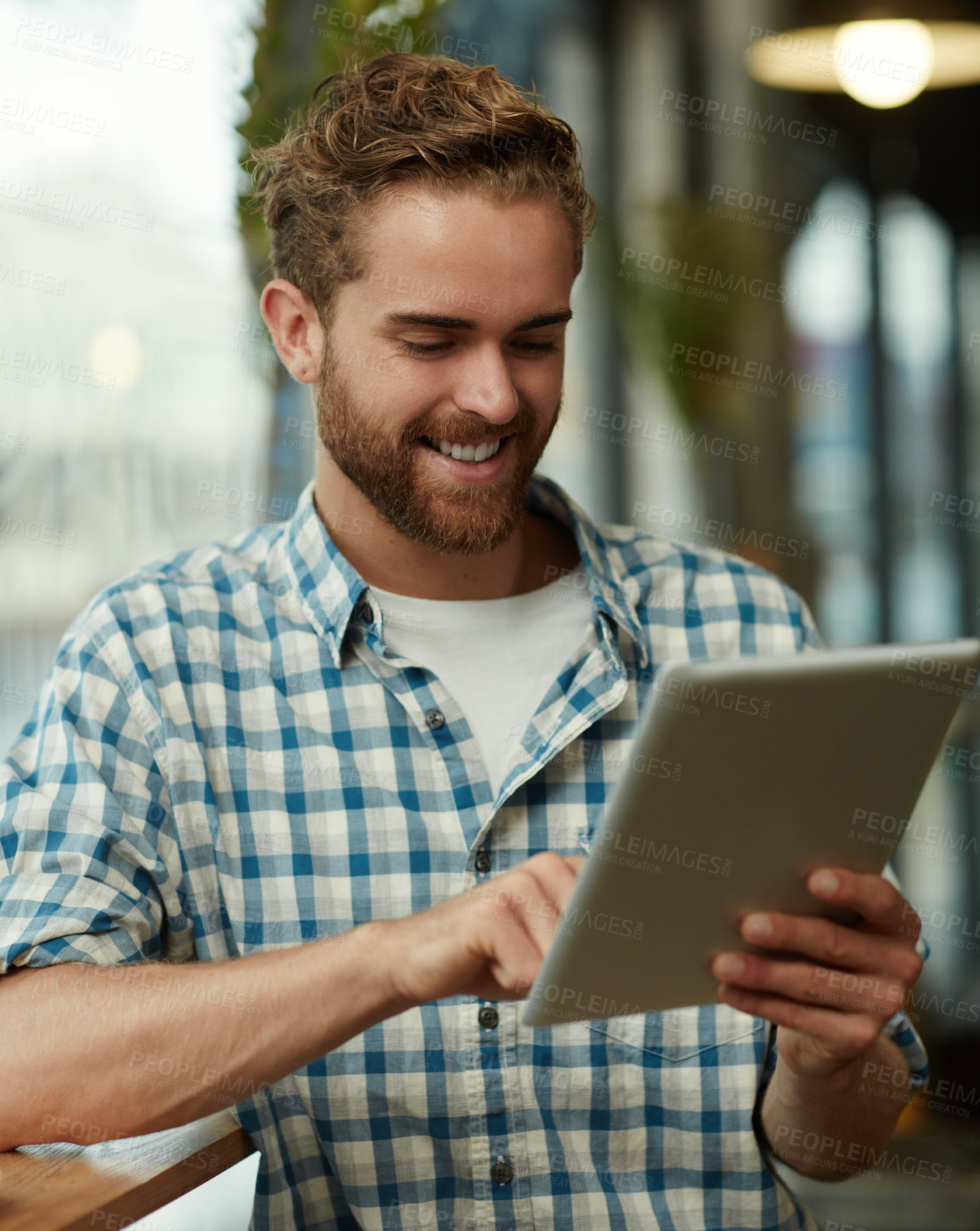 Buy stock photo Shot of a young man using a digital tablet in a cafe