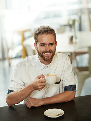 Buy stock photo Shot of a young man sitting at a table in a cafe