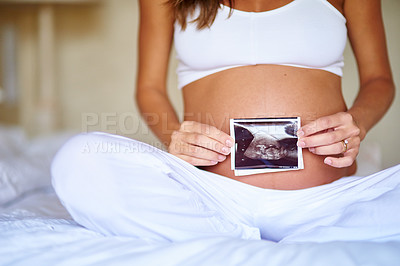 Buy stock photo Shot of a pregnant woman holding a sonogram picture in front of her belly