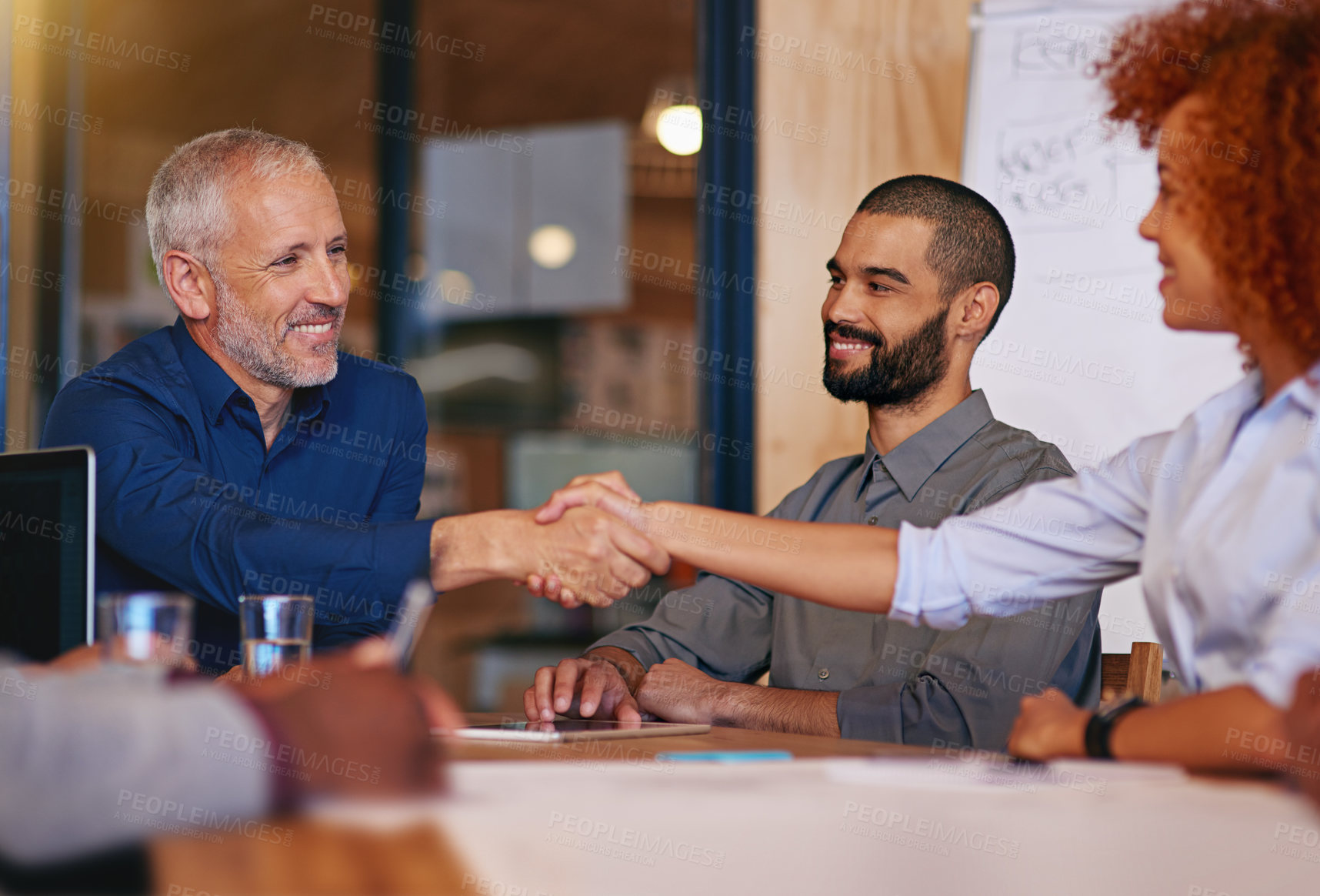 Buy stock photo Shot of colleagues shaking hands in an office meeting