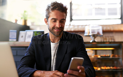 Buy stock photo Shot of a handsome young man using a phone and laptop in a cafe