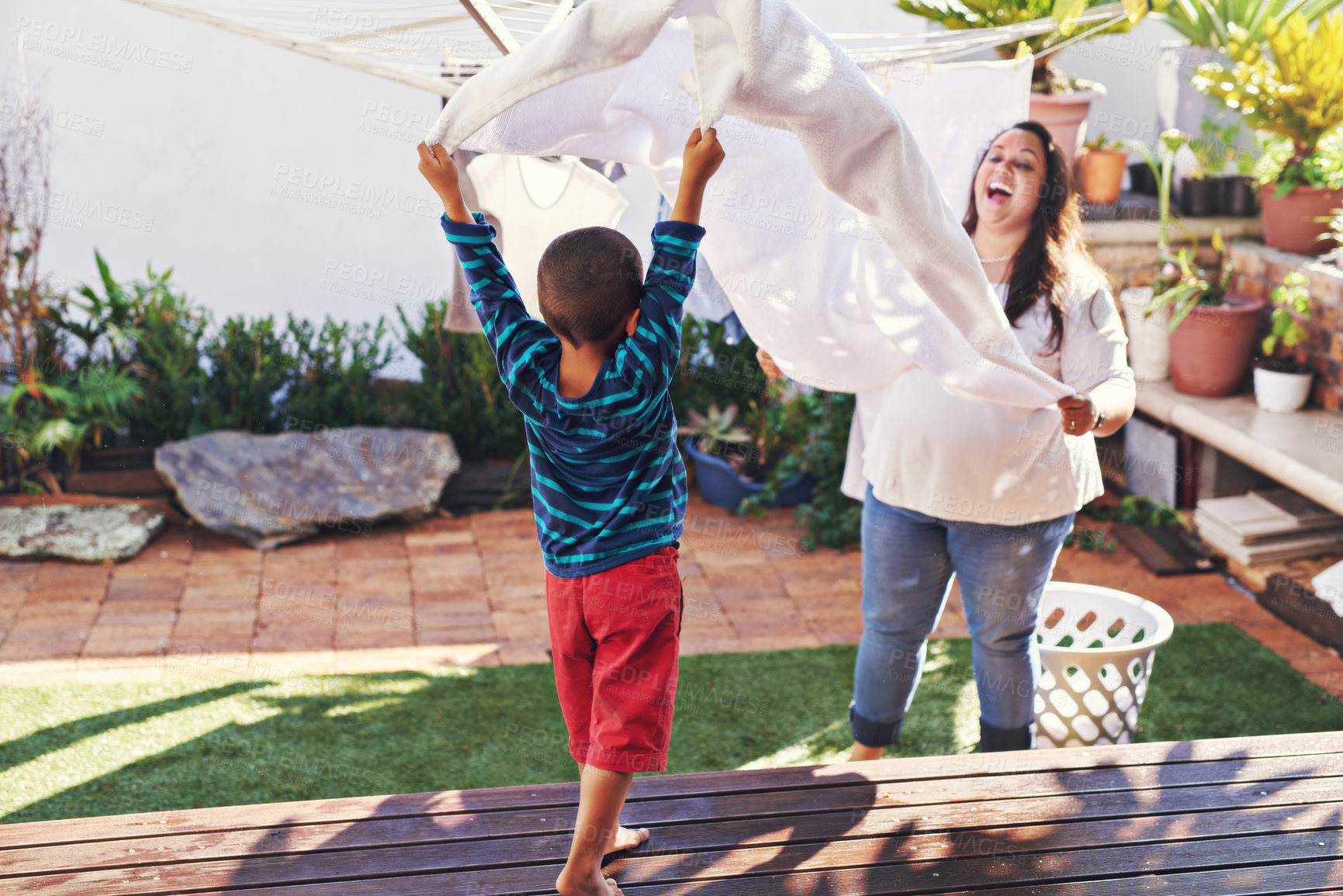 Buy stock photo Shot of a mother and son holding a towel out on the ends together