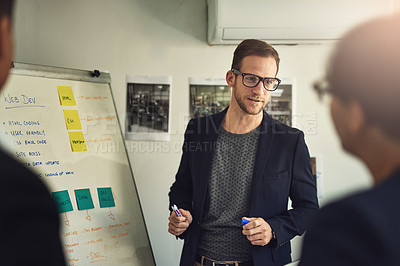 Buy stock photo Shot of a young man giving a presentation to colleagues in an office