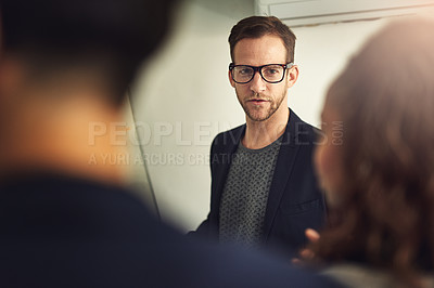 Buy stock photo Shot of a young man giving a presentation to colleagues in an office