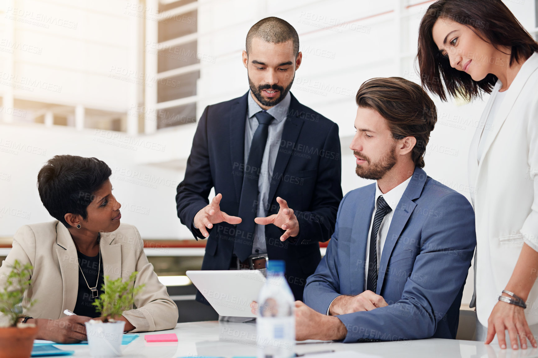 Buy stock photo Shot of businesspeople using a digital tablet in an office meeting