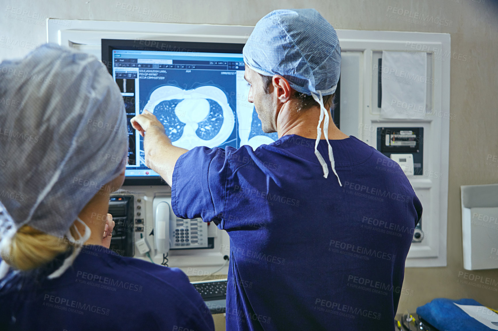 Buy stock photo Shot of a team of surgeons discussing a patient’s medical scans