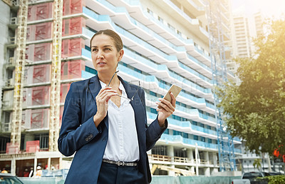 Buy stock photo Shot of a young businesswoman using her phone while out in the city