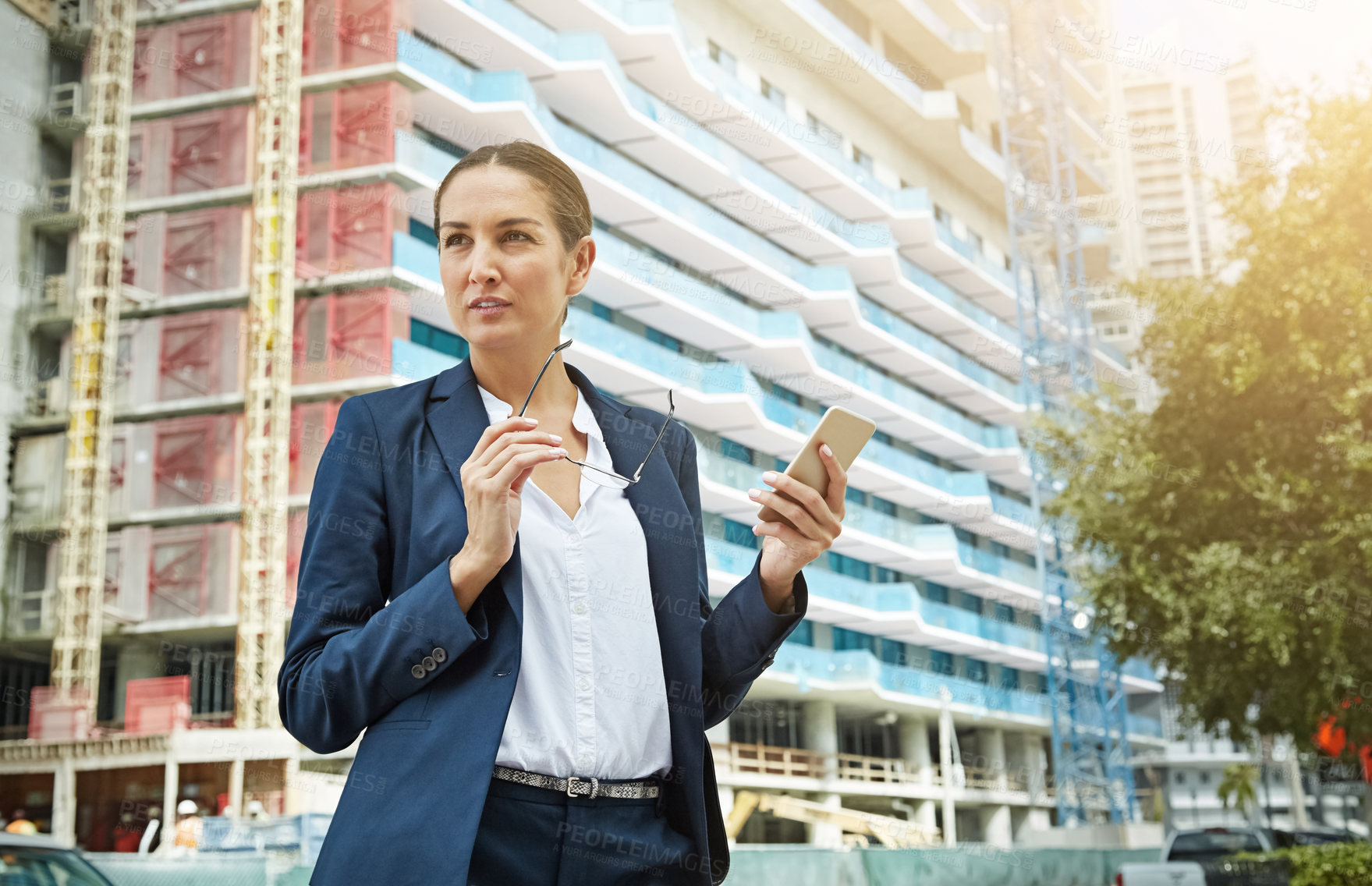 Buy stock photo Shot of a young businesswoman using her phone while out in the city