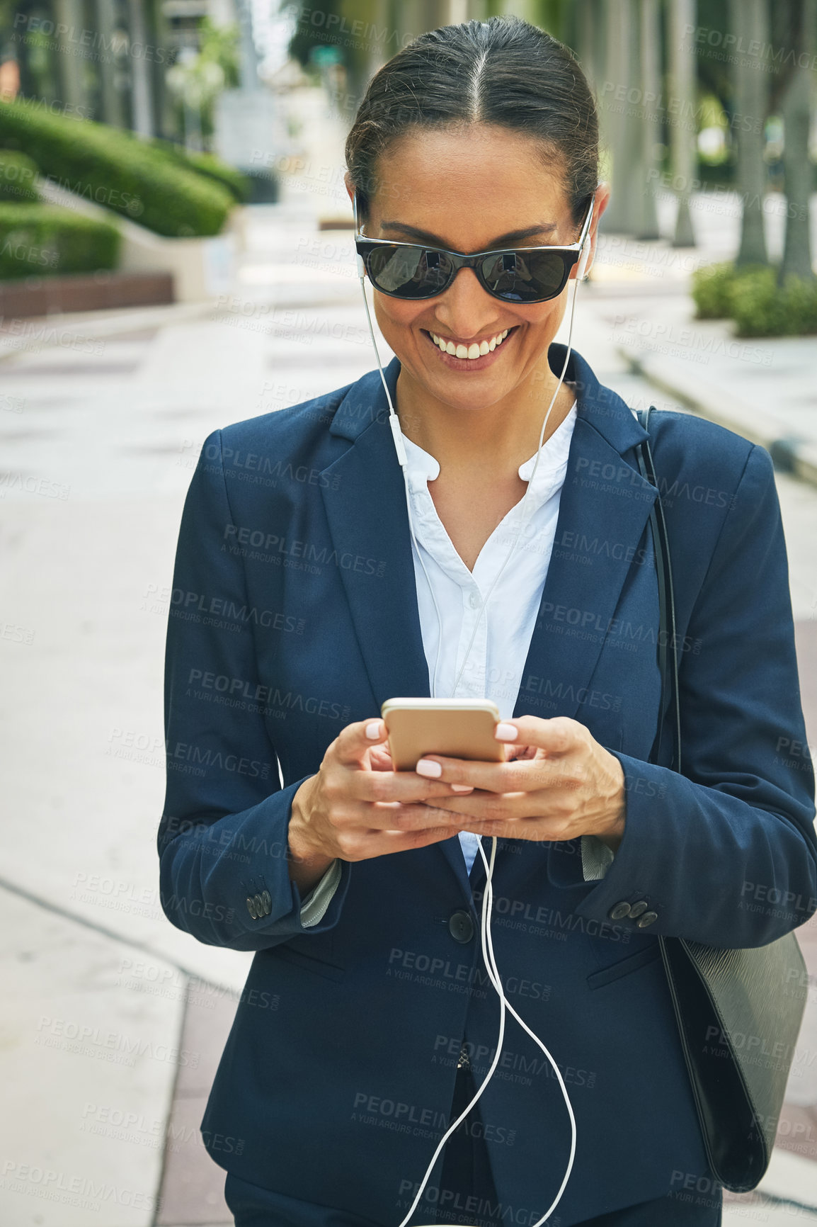 Buy stock photo Shot of a young businesswoman using her phone while out in the city