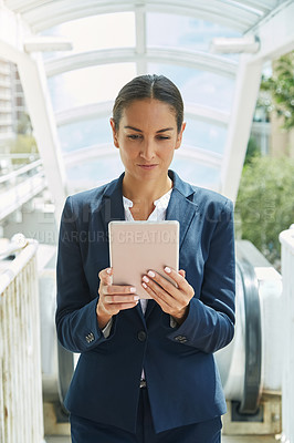 Buy stock photo Shot of a young businesswoman using a digital tablet on her way to the office