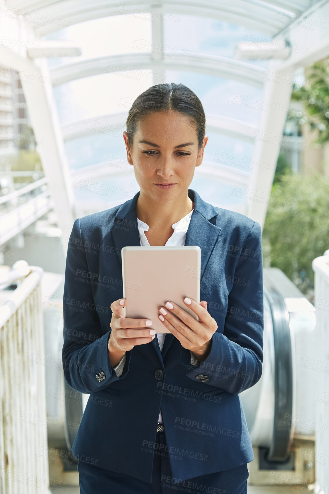 Buy stock photo Shot of a young businesswoman using a digital tablet on her way to the office