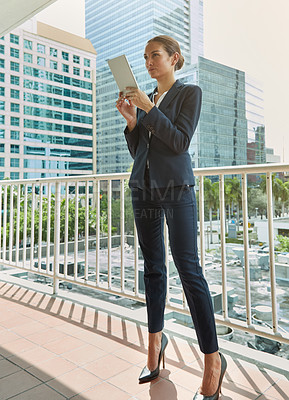 Buy stock photo Shot of a young businesswoman using a digital tablet on her way to the office