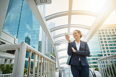 Buy stock photo Shot of a young businesswoman using a cellphone on the way to the office